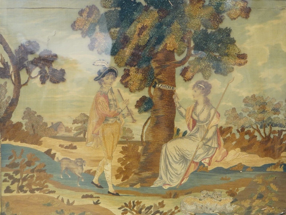 A gilt framed early 19th century silk chenille embroidered and hand painted figurative pastoral scene, framed with black and gold eglomise glass. The embroidery worked in a variety of stitches including stem and knotting